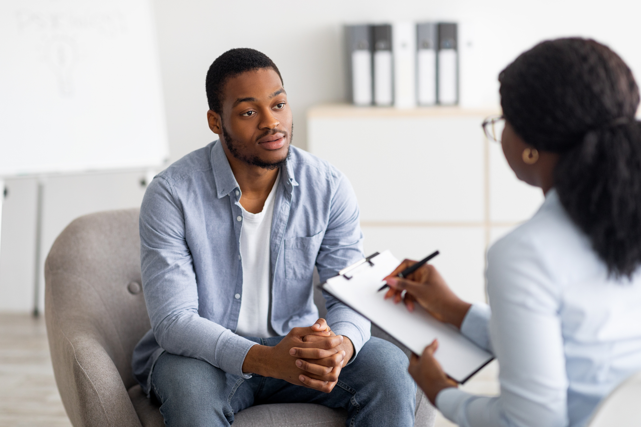Person in therapy session with counselor taking notes