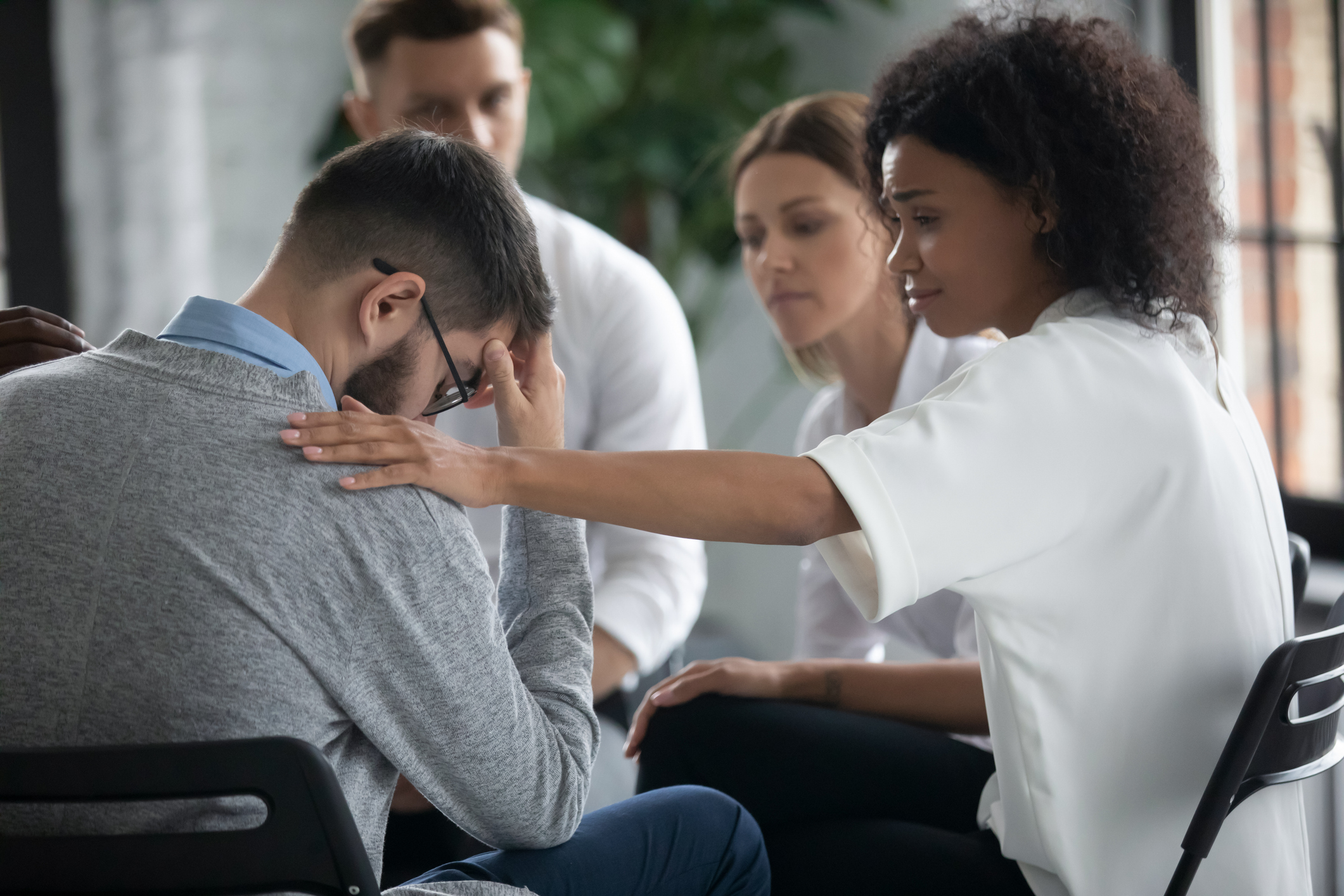 Woman comforting distressed man in support group