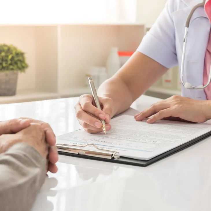 Nurse with stethoscope completing patient paperwork