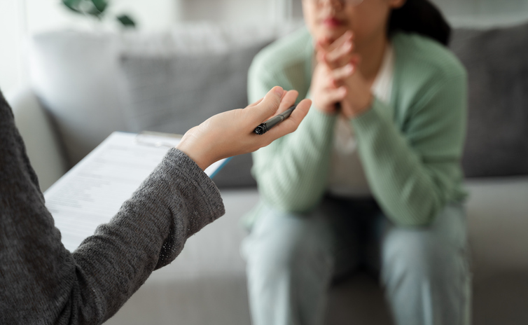 Therapist offering pen to patient on couch