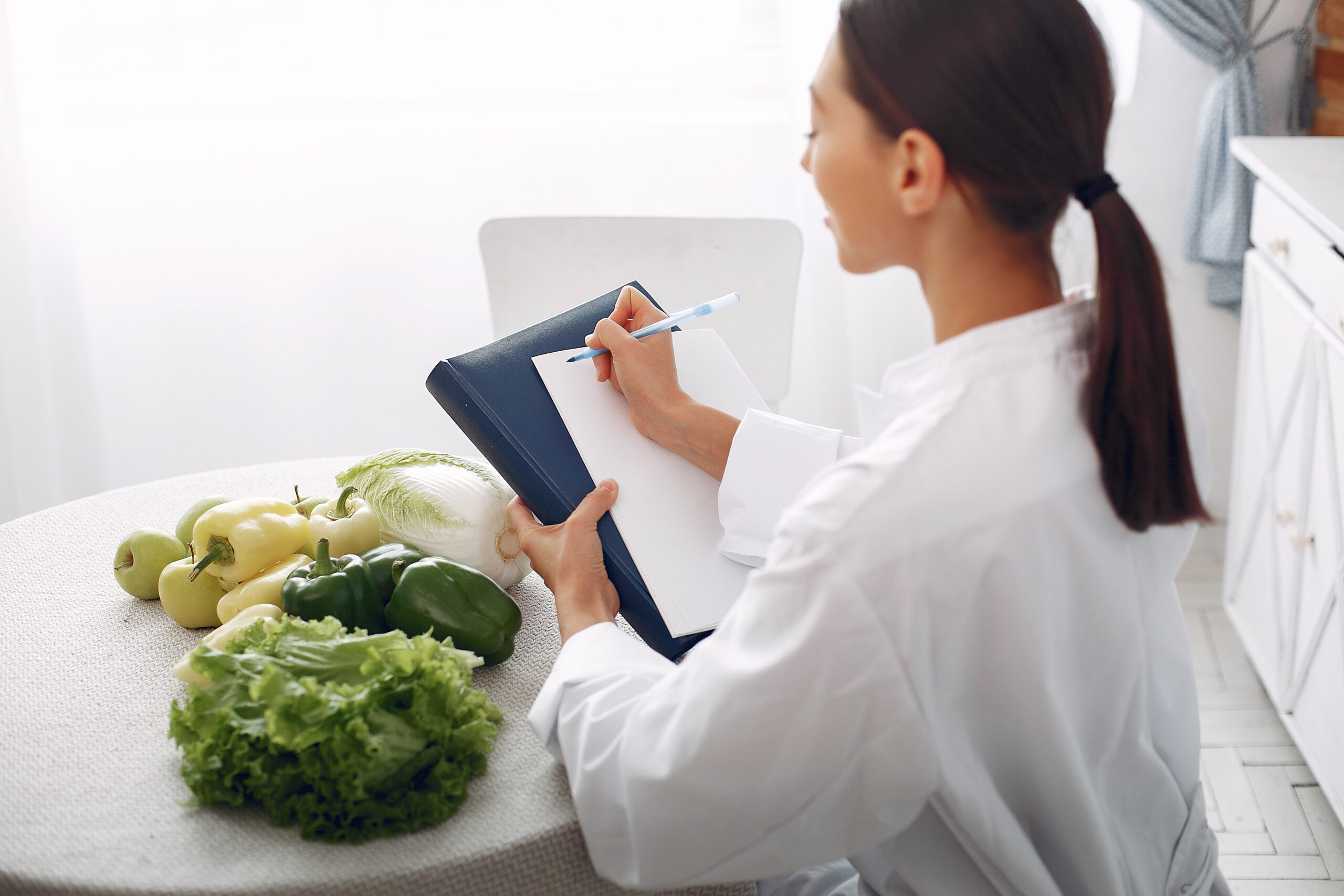 Person taking notes with clipboard near vegetables