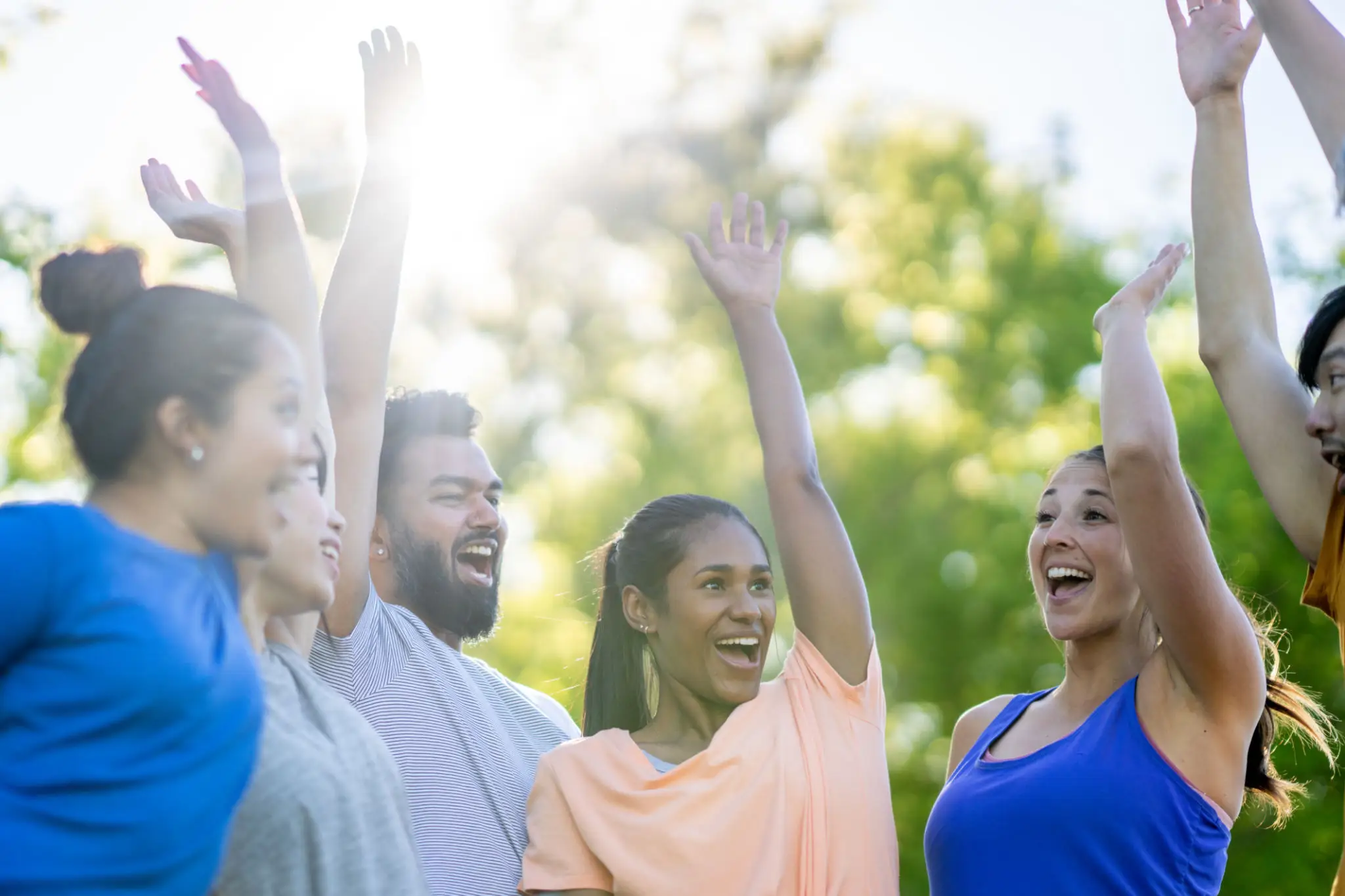 Group of friends cheering outdoors with raised hands