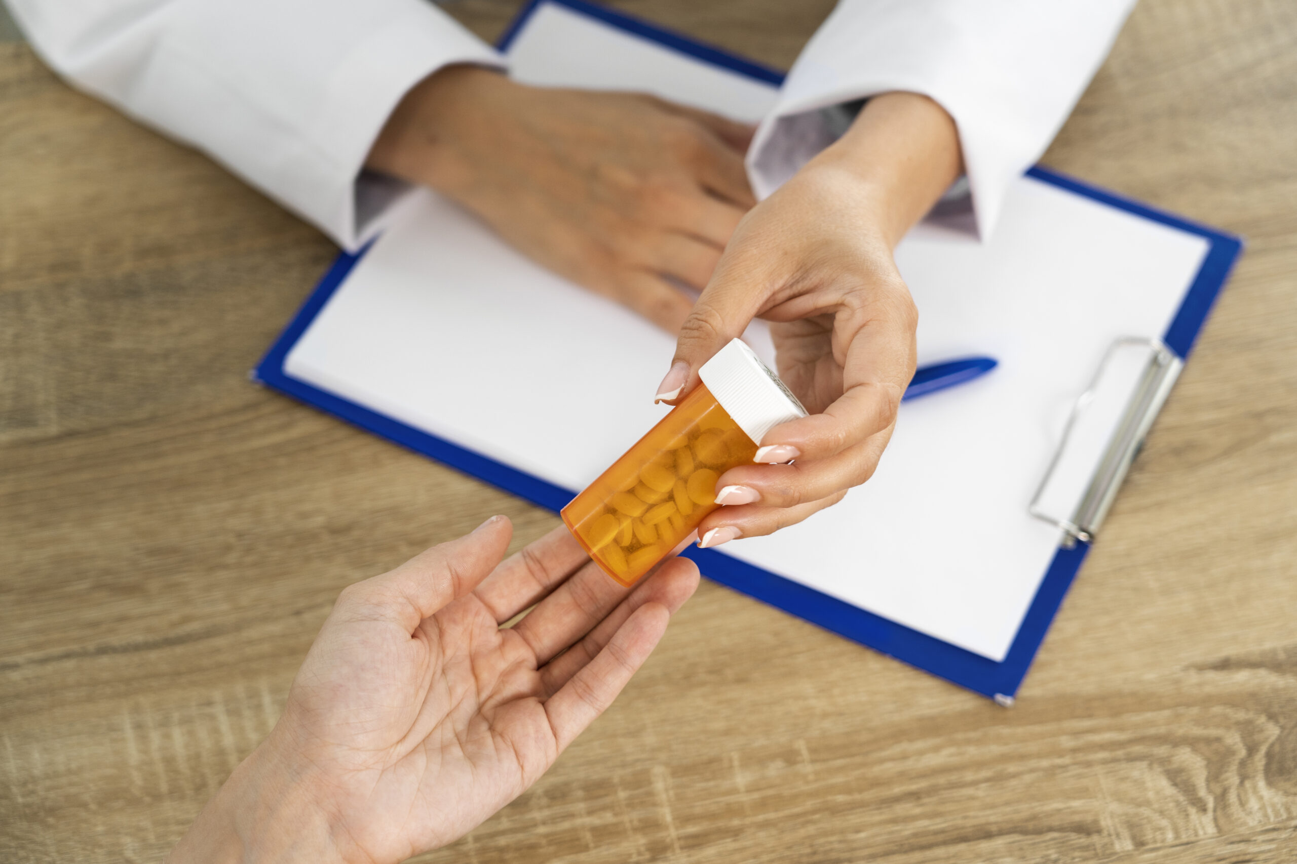 Doctor handing prescription bottle to patient