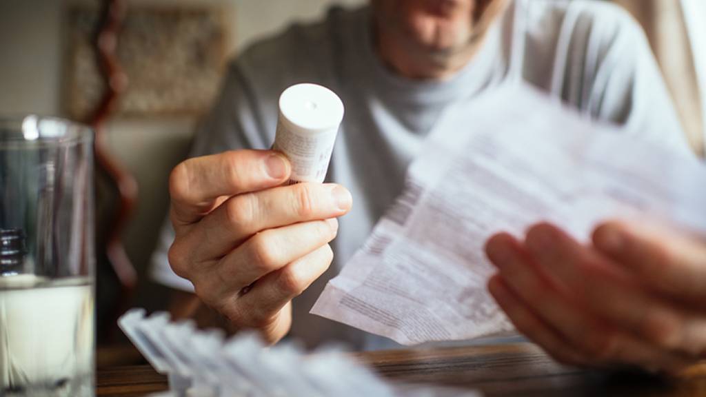 Person reading prescription bottle and leaflet