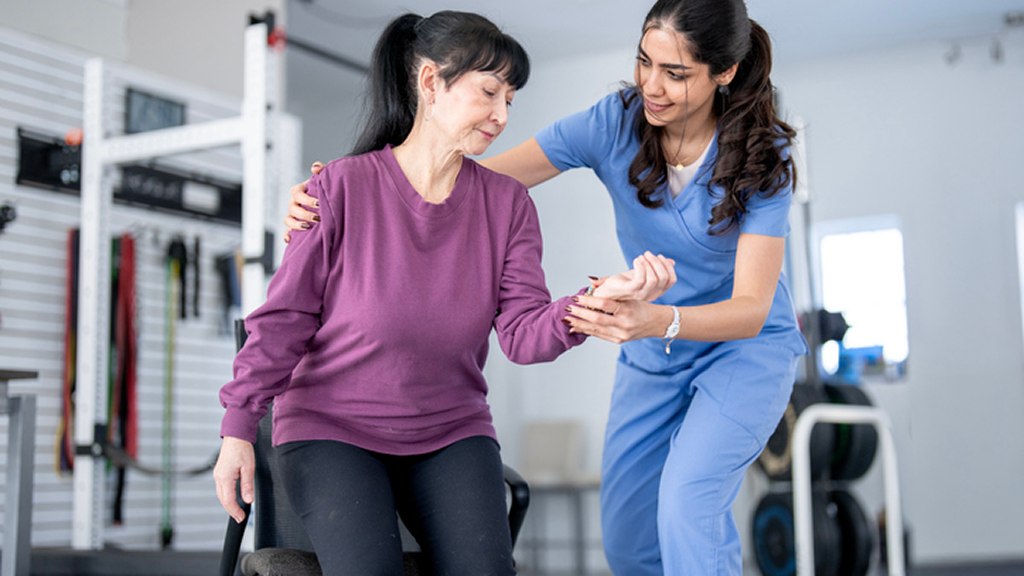 Physical therapist assisting senior woman with arm exercise