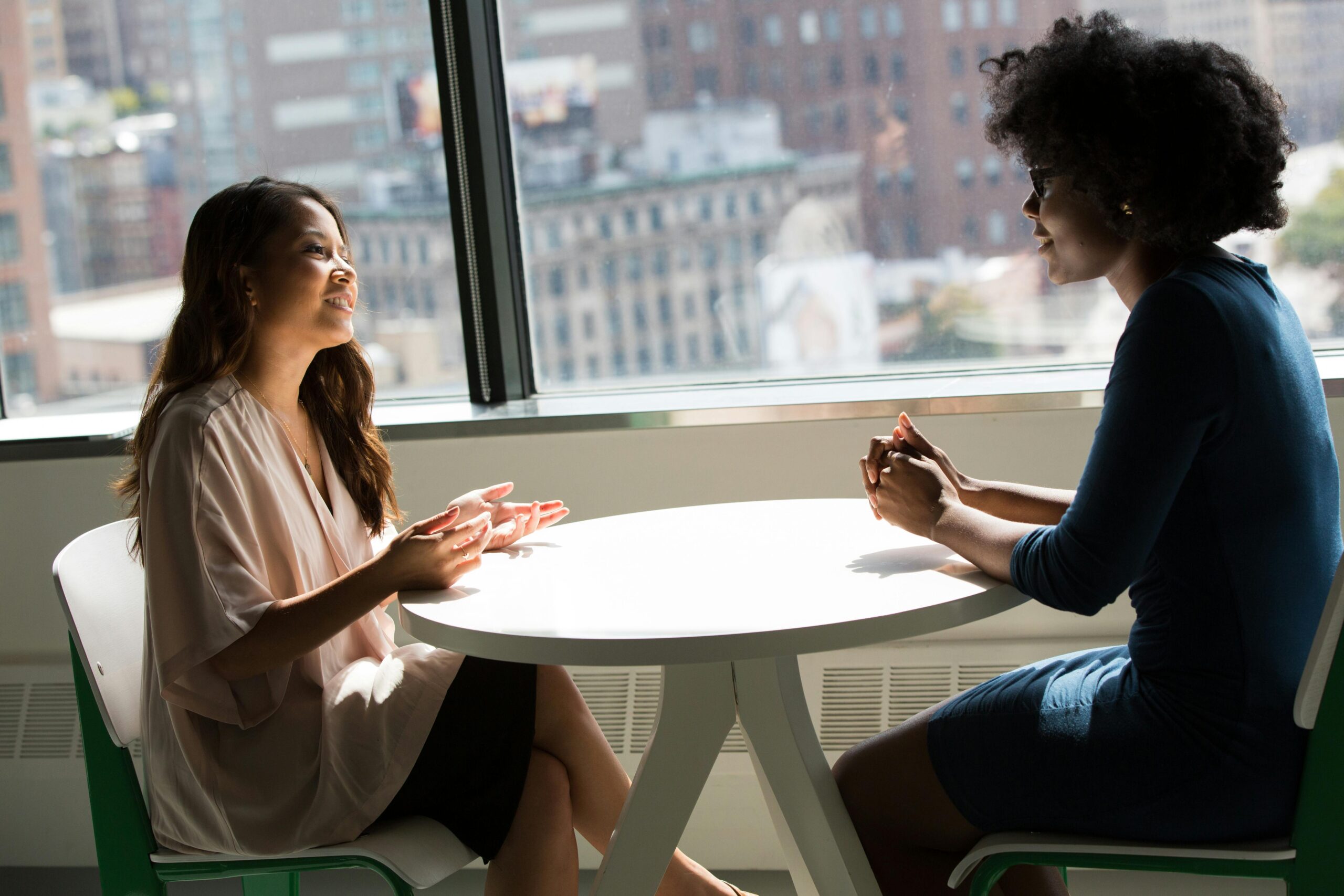 Two colleagues talking at round office table