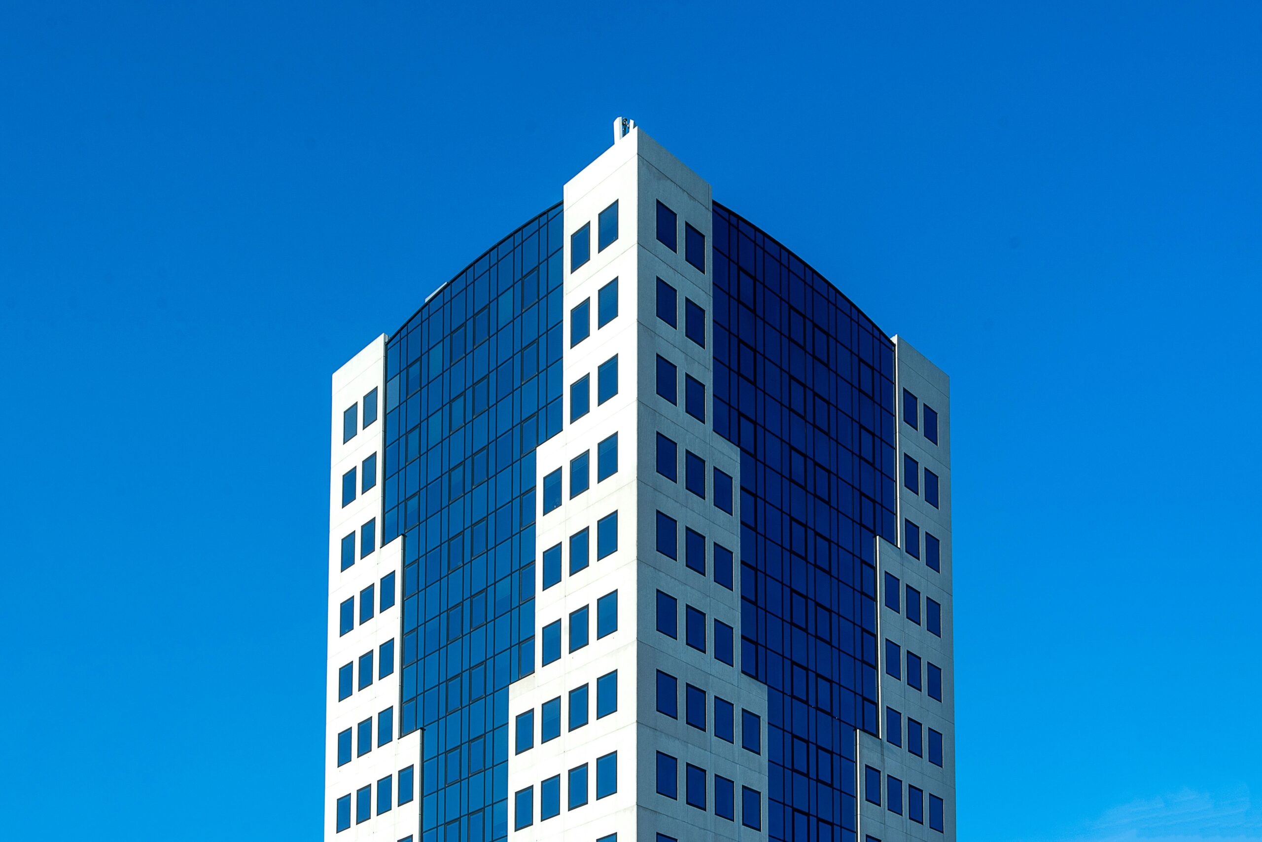 Modern glass office building against clear blue sky
