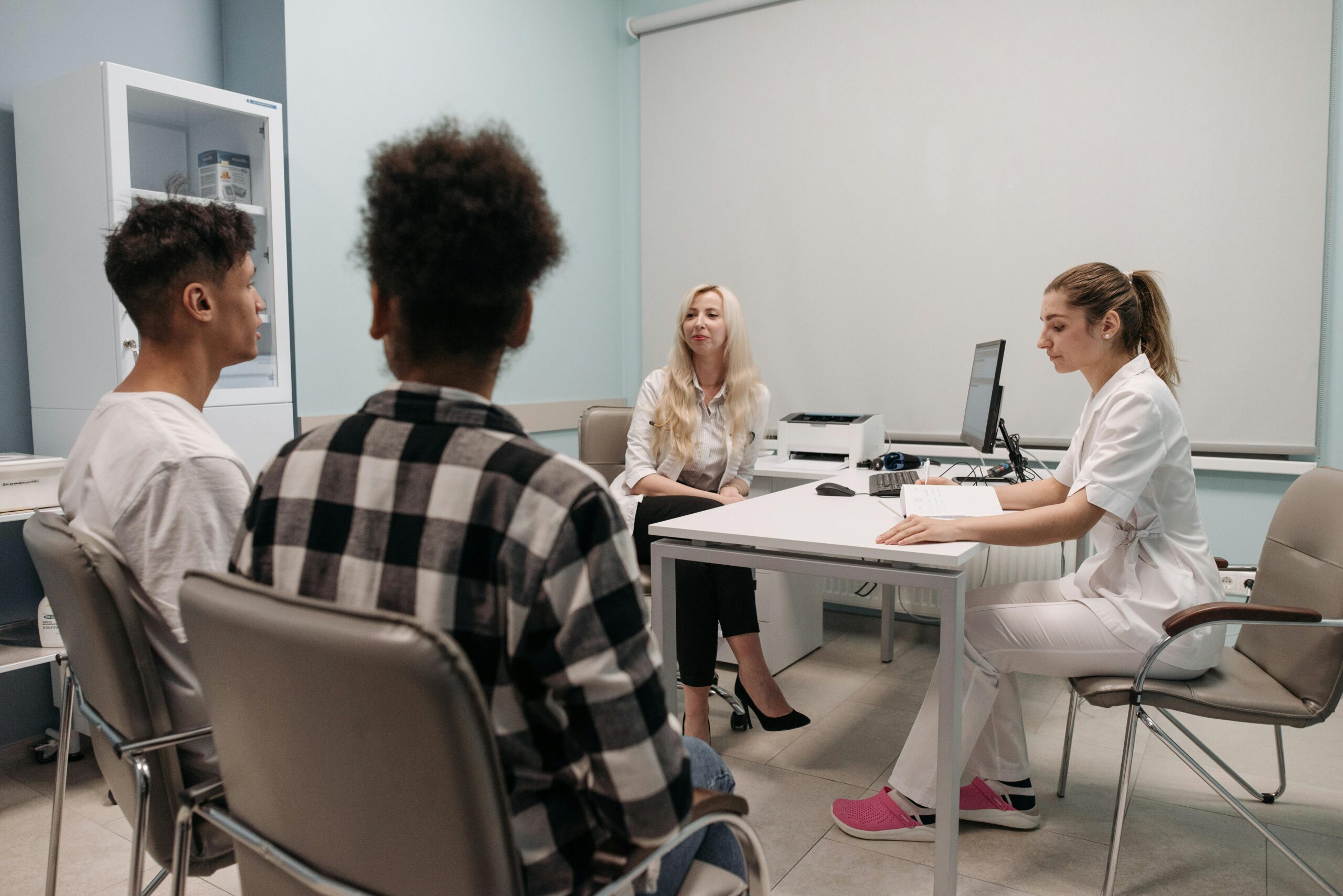 Healthcare provider consulting two patients in clinic