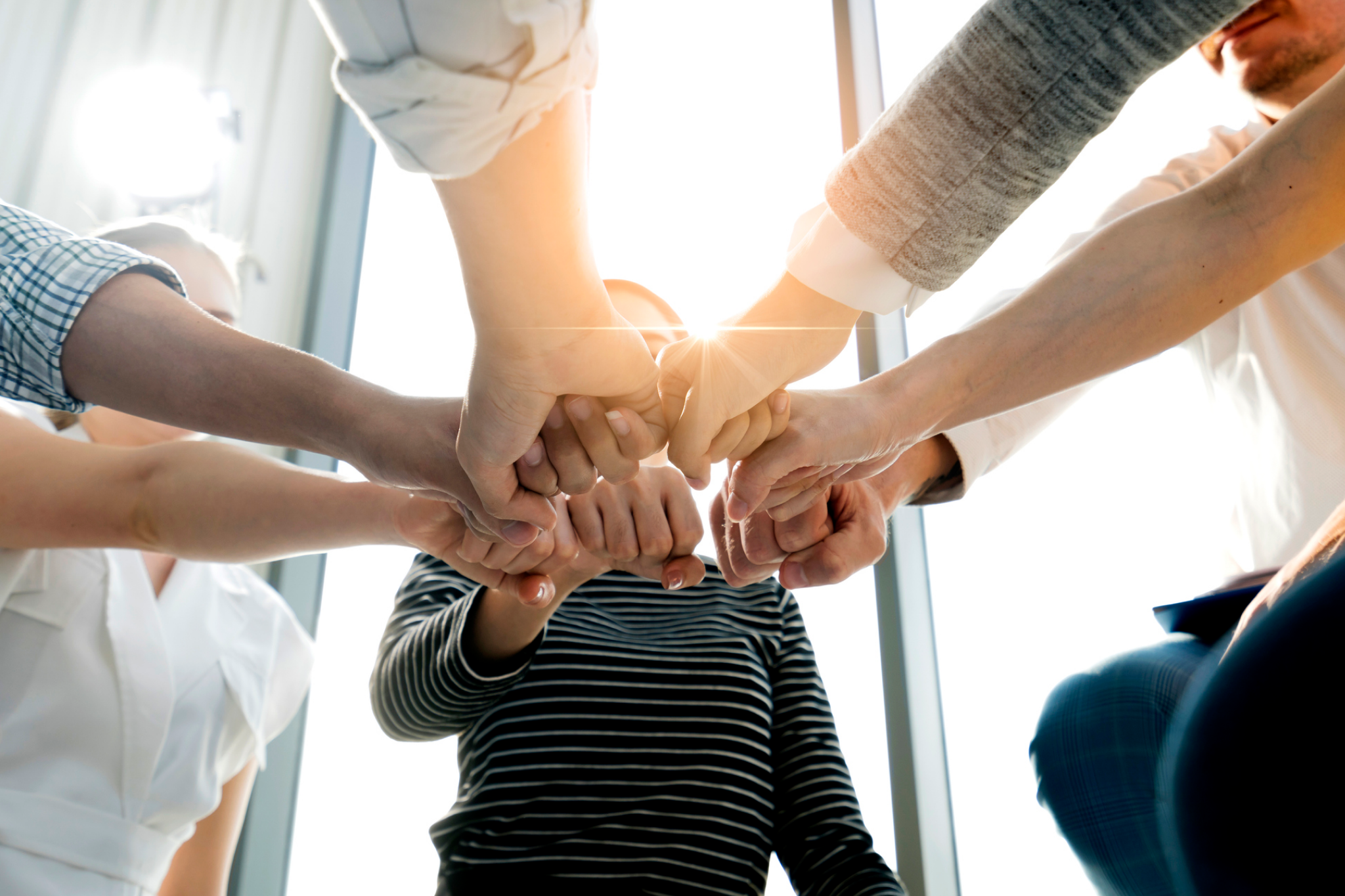 Colleagues joining hands in a team huddle