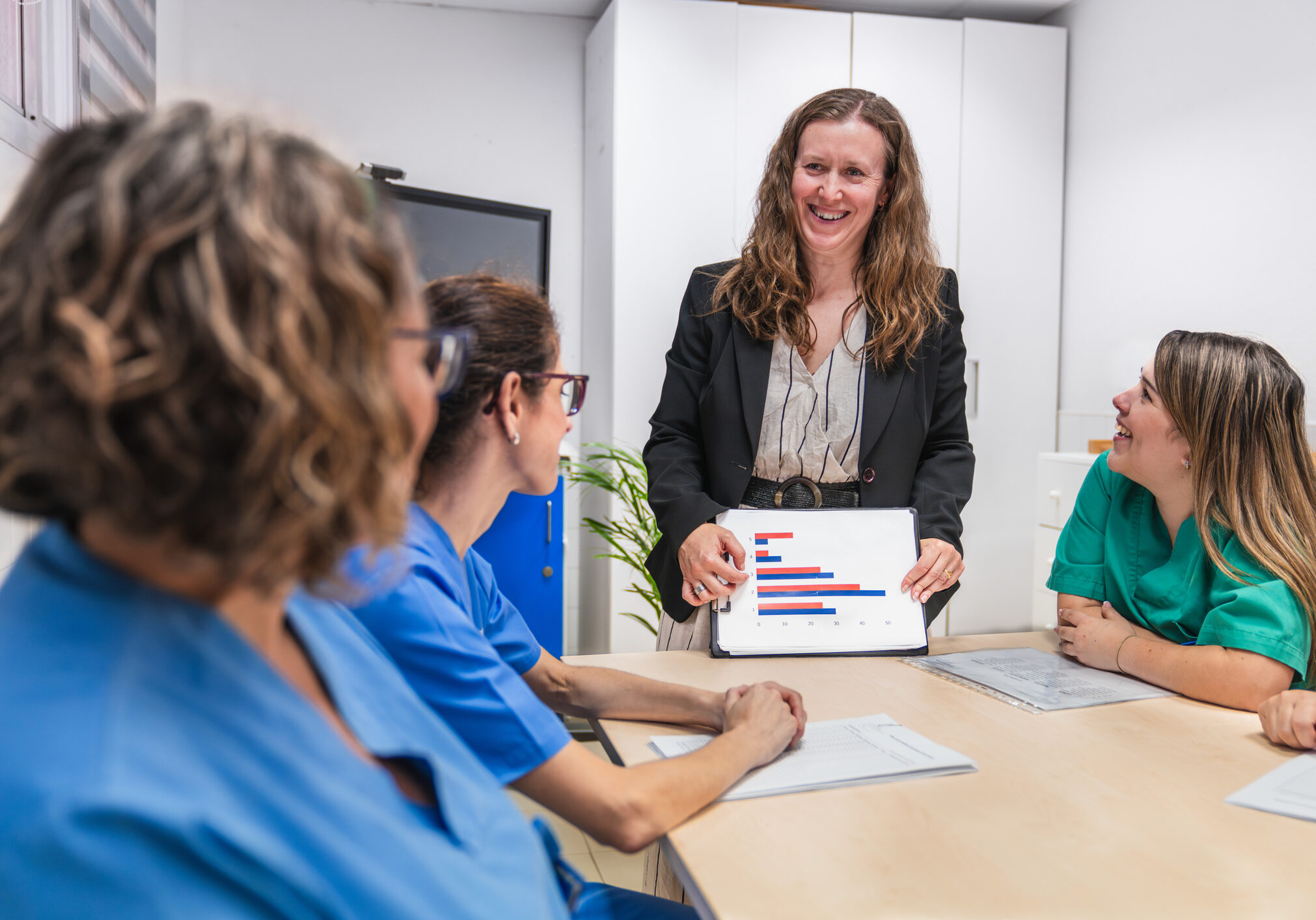 Woman presenting bar chart to medical team